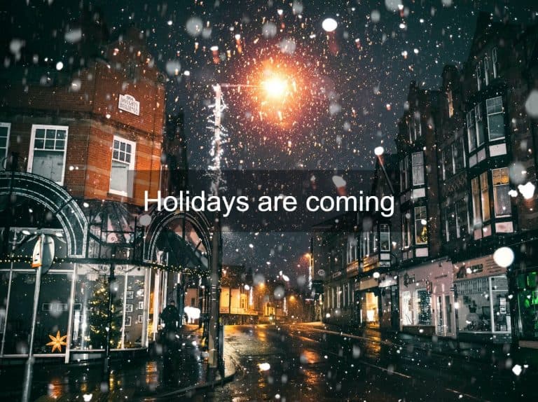 A street in winter while snow is falling and with a festive atmosphere
