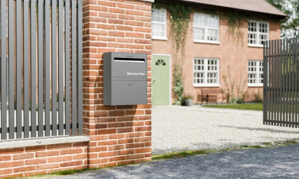Grey built-in parcel box mounted on a brick gate pier outside a UK home, secure solution for front door and driveway deliveries.