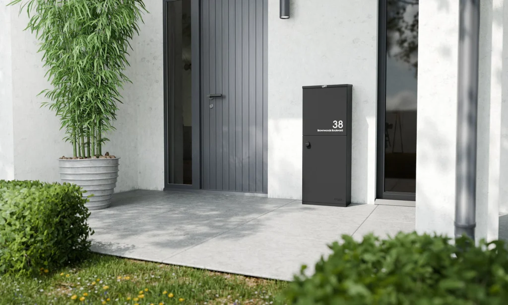 Modern black parcel box outside a contemporary UK home, wall-mounted style next to a grey front door.