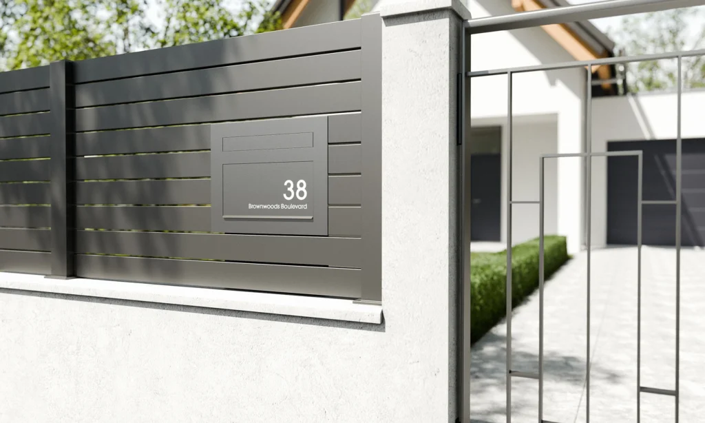 Modern gate-mounted letterbox on a contemporary UK home fence with house number panel.